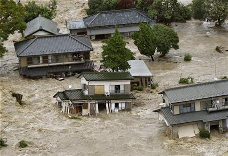 People inside houses wait to be rescued as the houses are submerged in water flooded from a river in Joso, Ibaraki prefecture, northeast of Tokyo Thursday, Sept. 10, 2015. AP