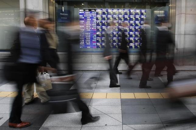 Passers-by walk past a stock quotation board outside a brokerage in Tokyo December 4, 2013.  REUTERS/Toru Hanai