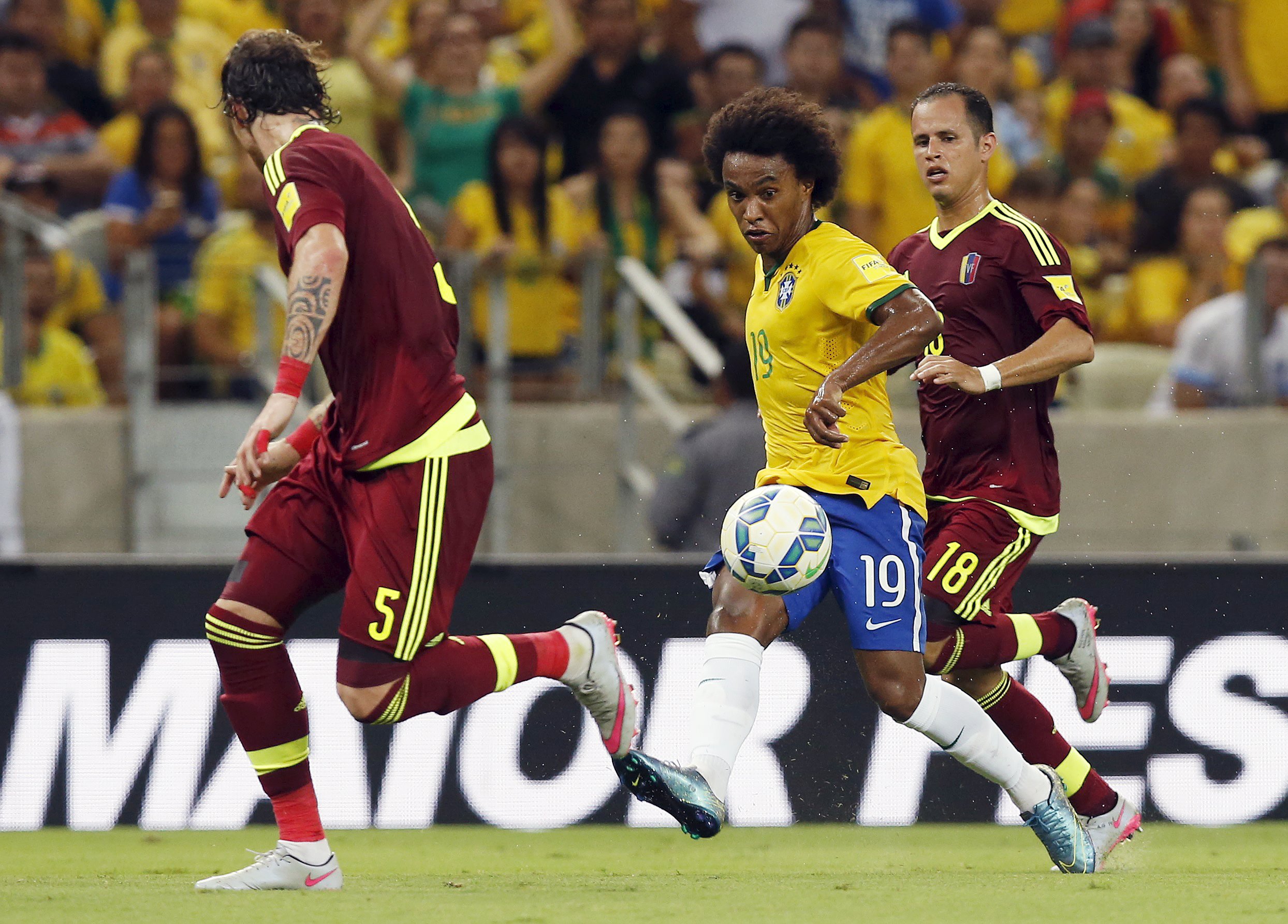 Willian (C) of Brazil kicks the ball between Fernando Amorebieta (L) and Alejandro Guerra of Venezuela during their 2018 World Cup qualifying soccer match in Fortaleza, Brazil, October 13, 2015.   REUTERS/Paulo Whitaker