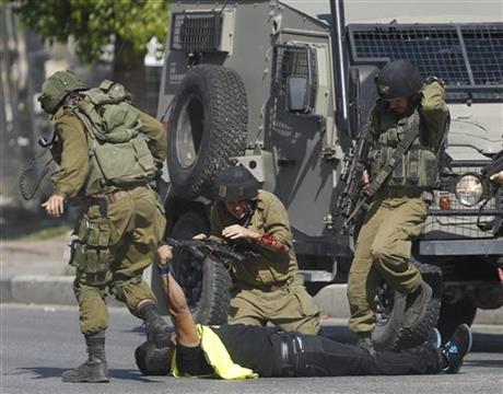 In this Friday, Oct. 16, 2015, file photo, an Israeli soldier runs to help another who was just stabbed by a Palestinian, seen on the ground holding a knife, during clashes in Hebron, West Bank. Photo: AP