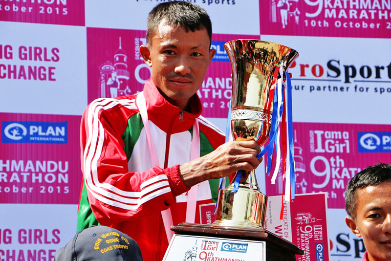 Purna Tamang of TAC  holds his trophy after winning the Kathmandu Marathon title at the Dasharath Stadium in Kathmandu on Saturday.Courtesy: Plan International
