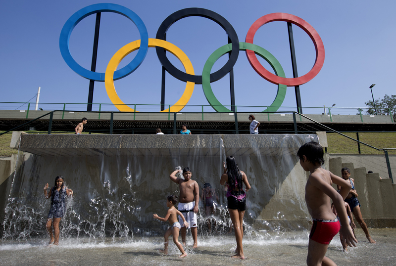 FILE - In this July 28, 2015 file photo, children play in a water fountain next to Olympic rings at Madureira Park in Rio de Janeiro, Brazil. Some foreign ticket buyers for next year's Rio Olympics are paying higher prices than they should, failing to benefit from the steep decline in the value of the Brazilian currency against the dollar. (AP Photo/Silvia Izquierdo, File)