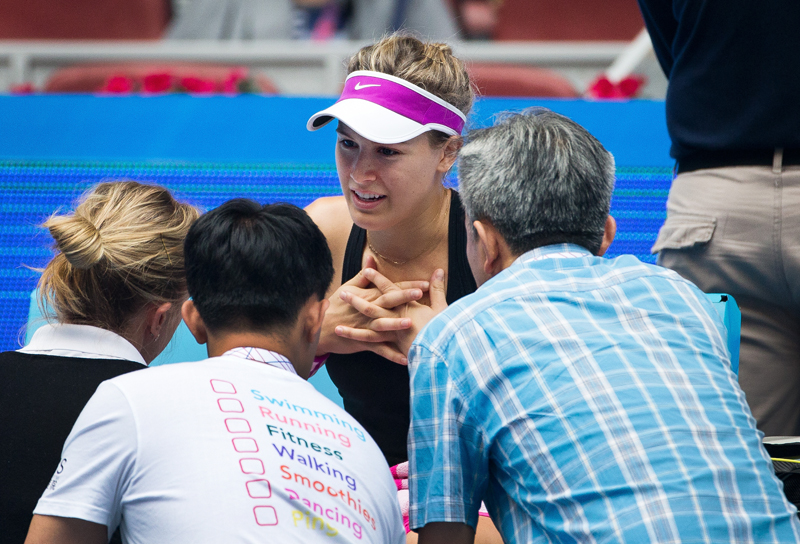 Eugenie Bouchard of Canada, center, talks with medical staff before retiring from her first round match against Andrea Petkovic of Germany at the China Open tennis tournament at the National Tennis Stadium in Beijing, Monday, Oct. 5, 2015. (AP Photo/Andy Wong)