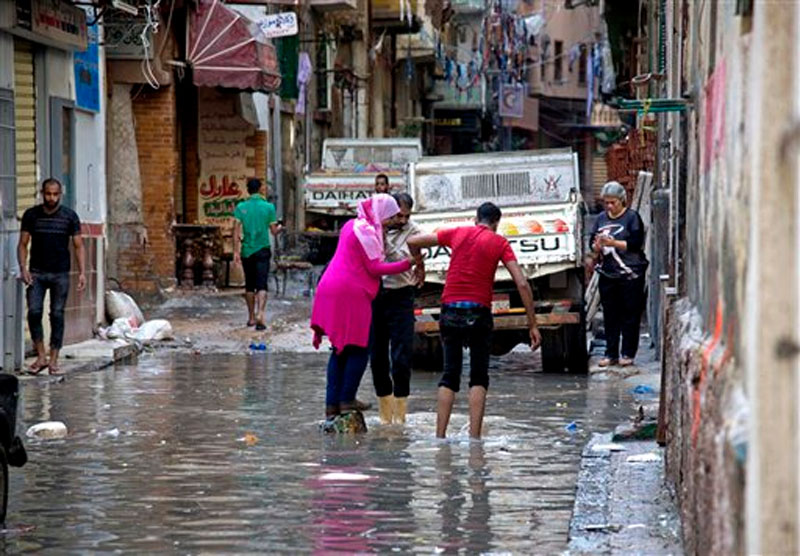 Egyptians walk through water after a heavy rainfall in the coastal city of Alexandria, Egypt, Sunday, October 25, 2015. Photo: AP