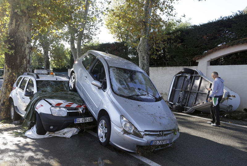 A man walks past damaged cars in Biot, near Cannes, southeastern France, Sunday Oct.4, 2015. Sudden heavy rains around the French Riviera have killed at least 10 people, including some trapped in cars, a campsite and a retirement home, and left six missing. Car and train traffic was disrupted along the Mediterranean coast. (AP Photo/Lionel Cironneau)