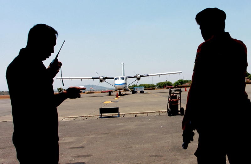 Military personnel talk on radio near a Twin Otter plane similar to the one that is reported missing on Friday, at Sultan Hasanuddin airport in Makassar, South Sulawesi, Indonesia, Saturday, Oct. 3, 2015. An air and ground search is underway Saturday for a small passenger plane that went missing with 10 people on board during a domestic flight in eastern Indonesia. (AP Photo/Masyudi S. Firmansyah)