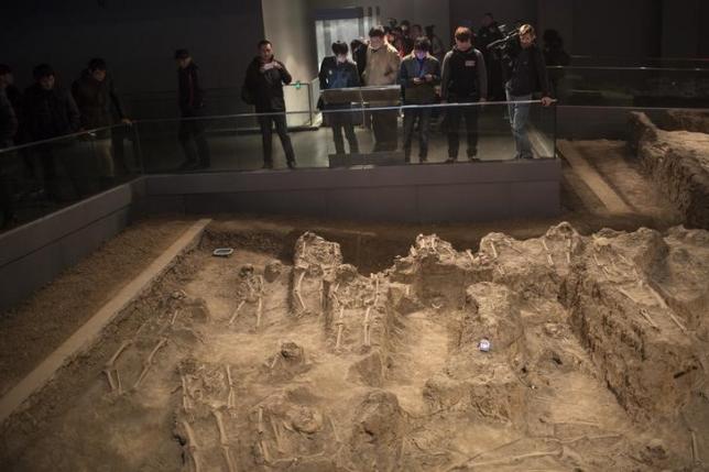 Journalists and visitors look at skeletons of victims of the 1937 Nanjing massacre at the Nanjing Massacre Museum during a media trip, in Nanjing, Jiangsu province, February 19, 2014. REUTERS/Aly Song/Files