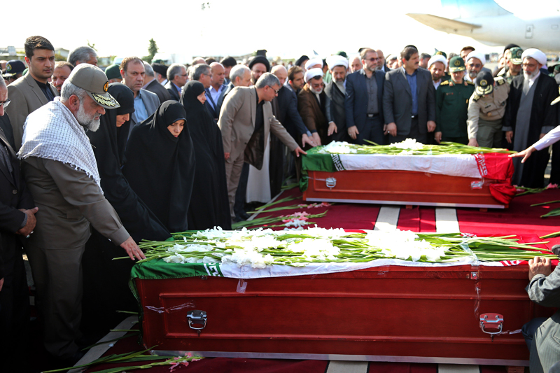 Iranian officials pray as they touch the coffin of a dead hajj pilgrim who was killed in a deadly stampede in Mina near Mecca in Saudi Arabia on September 24, at Mehrabad airport in Tehran, Iran, Saturday, Oct. 3, 2015. The first plane carrying bodies of Iranian pilgrims killed in the hajj stampede in Saudi Arabia arrived in Tehran Saturday, nine days after the disaster that escalated tensions between the two regional rivals. President Hassan Rouhani and other senior officials were at the airport for the arrival of the plane, which carried 104 bodies. (AP Photo/Ebrahim Noroozi)