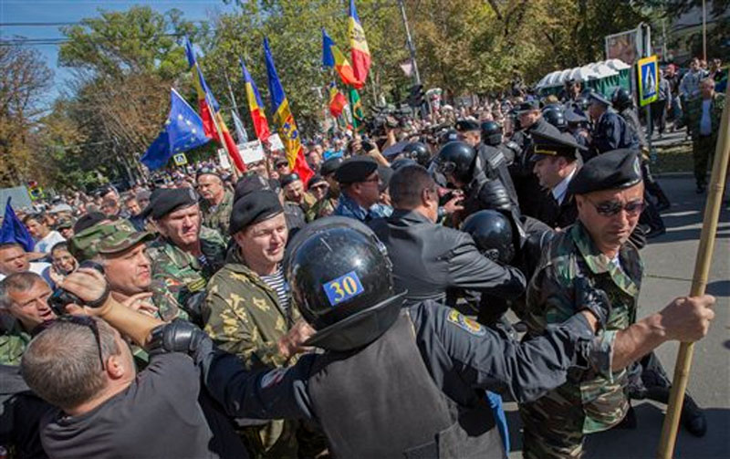 People break through a line of Moldovan riot policemen outside the parliament building in Chisinau, Moldova, Sunday, October 4, 2015. Photo: AP
