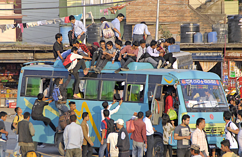 Passengers climbing on the roof of a bus at Old Bus Park, Kathmandu, on Wednesday, September 30. Very few public vehicles have been operating in the capital due to crisis of petroleum products. Photo: THT