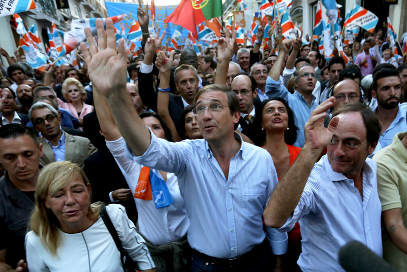Portuguese Prime Minister Pedro Passos Coelho, center, and Deputy Prime Minister Paulo Portas, right, wave during an election campaign march in Lisbon, Portugal, Friday, Oct. 2, 2015. Portugal goes to the polls to elect a new government on Sunday. (AP Photo/Armando Franca)