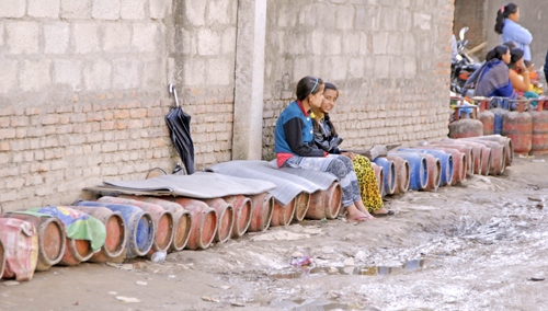 Girls sitting on empty cylinders as they wait in queue for cooking gas, in Balkumari, Lalitpur, on Friday. Photo: THT