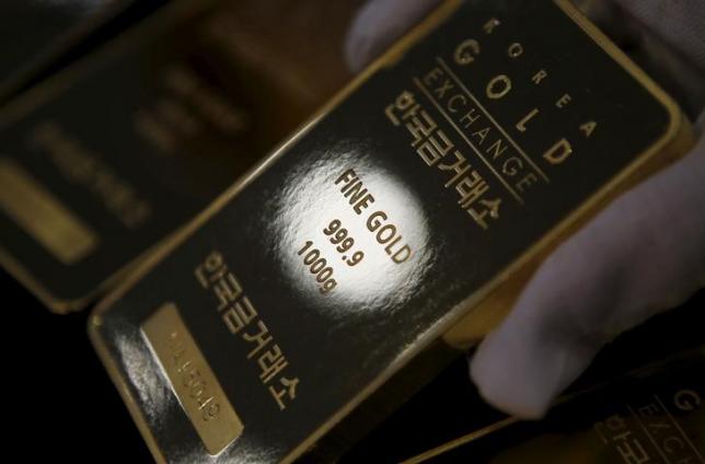 An employee poses for photographs with one kilogram gold bars at the Korea Gold Exchange in Seoul, South Korea, July 31, 2015. REUTERS/Kim Hong-Ji