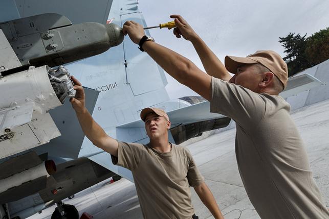 Russian ground staff members work on a Sukhoi Su-30 fighter jet at the Hmeymim air base near Latakia, Syria, in this handout photograph released by Russia's Defence Ministry October 22, 2015. REUTERS/Ministry of Defence of the Russian Federation/Handout via Reuters