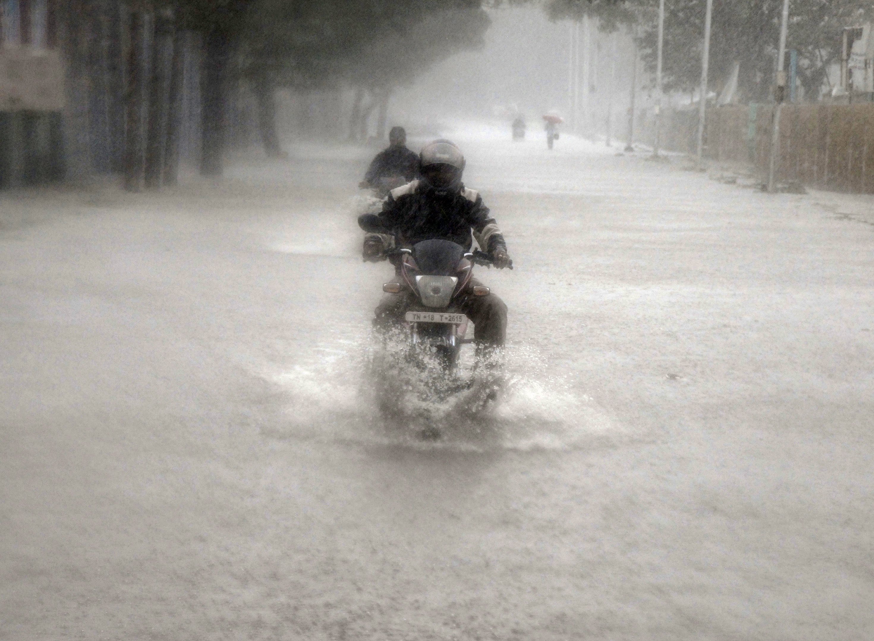 A man rides his motorbike through a flooded road during heavy rain in Chennai, India, November 9, 2015. Photo: Reuters