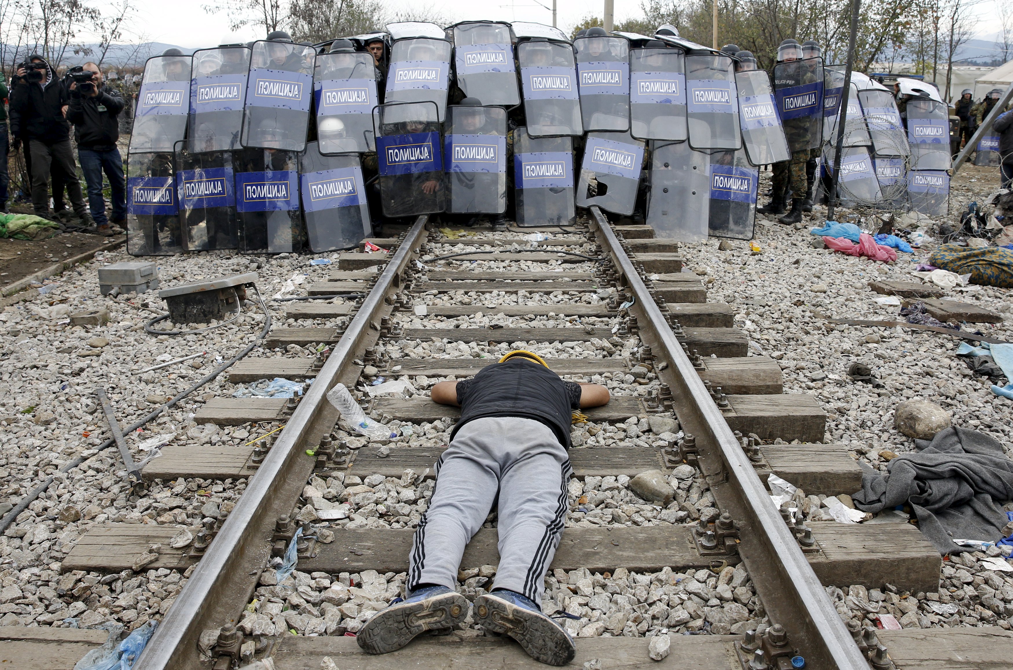 REFILE - CORRECTING REASON OF CLASHA stranded migrant lays on the rail tracks in front of a Macedonian police cordon as they clash after a migrant was injured when he climbed on top of a train wagon, near the village of Idomeni, Greece, November 28, 2015. REUTERS/Yannis Behrakis