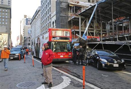 Bystanders look on next to an open-air tour bus, at right under scaffolding, that crashed into a construction site near Union Square Friday, Nov. 13, 2015, in San Francisco. Photo: AP