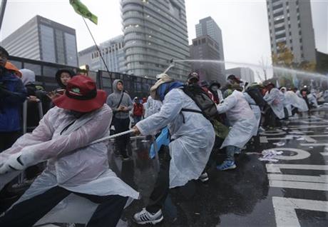 South Korean protesters pull a wire to remove a police bus as they try to march to the Presidential House after a rally against government policy in Seoul, South Korea, Saturday, Nov. 14, 2015. Photo:AP