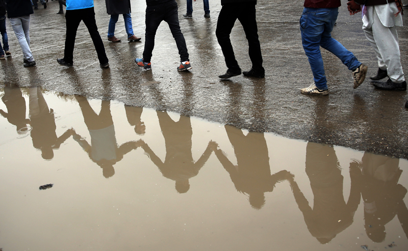 Protesters are reflected in a puddle as thousands march through the Afghan capital of Kabul on Wednesday, Nov. 11, 2015, carrying the coffins of seven ethnic Hazaras who were allegedly killed by the Taliban and calling for a new government that can ensure security in the country. Photo: AP