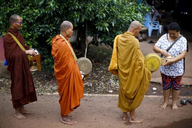 Buddhist monks receive rice from women early morning in a village outside Nong Khai, Thailand September 16, 2015. REUTERS/Jorge Silva/files