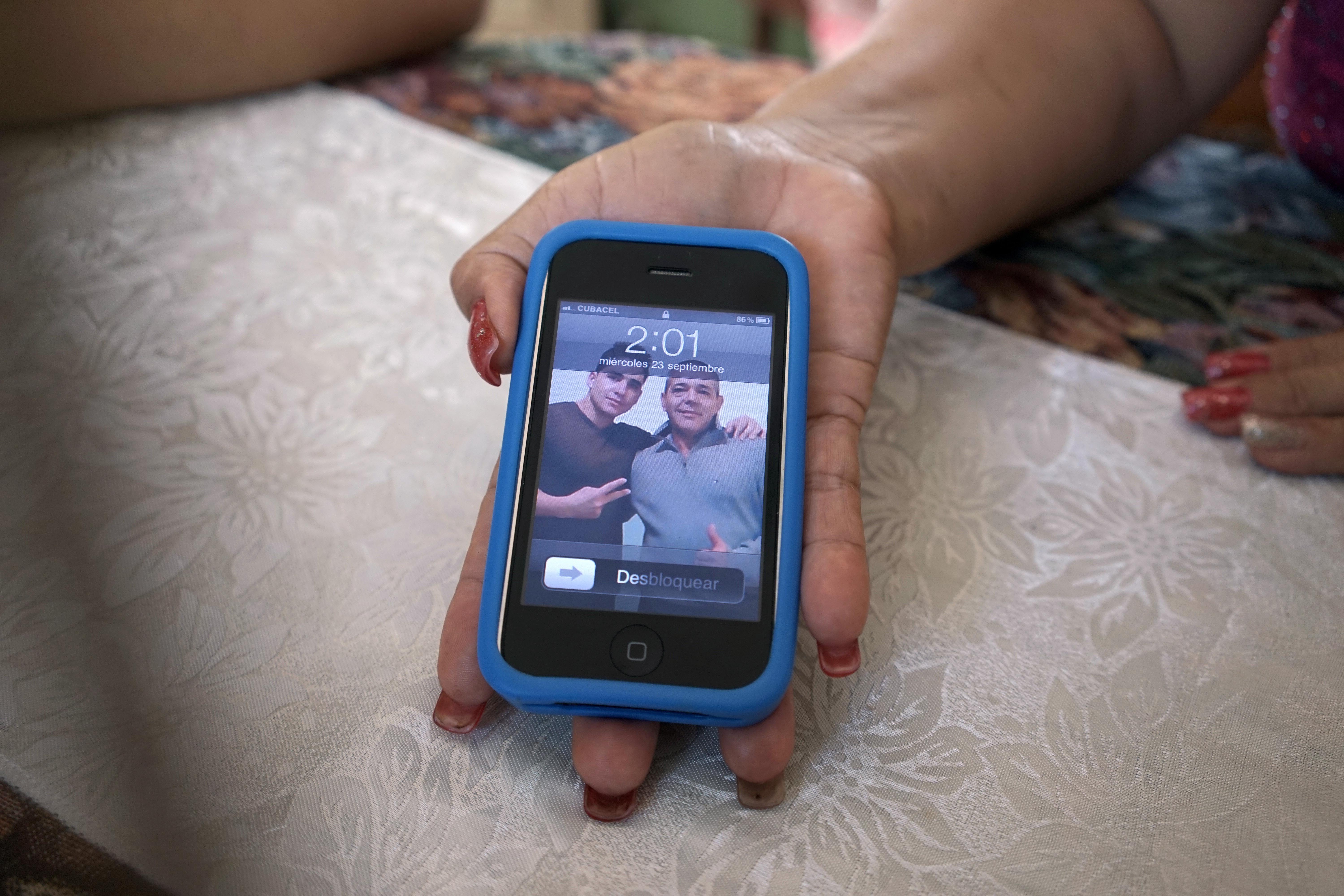 Olea Lastre, a hairdresser, shows a photo of her husband Antonio Cardenas with her son Jose Fuentes Lastre, taken in the US after they survived 10 days at sea on a raft in the Florida Straits, on her cell phone in Camaguey, Cuba. Photo: AP/ File