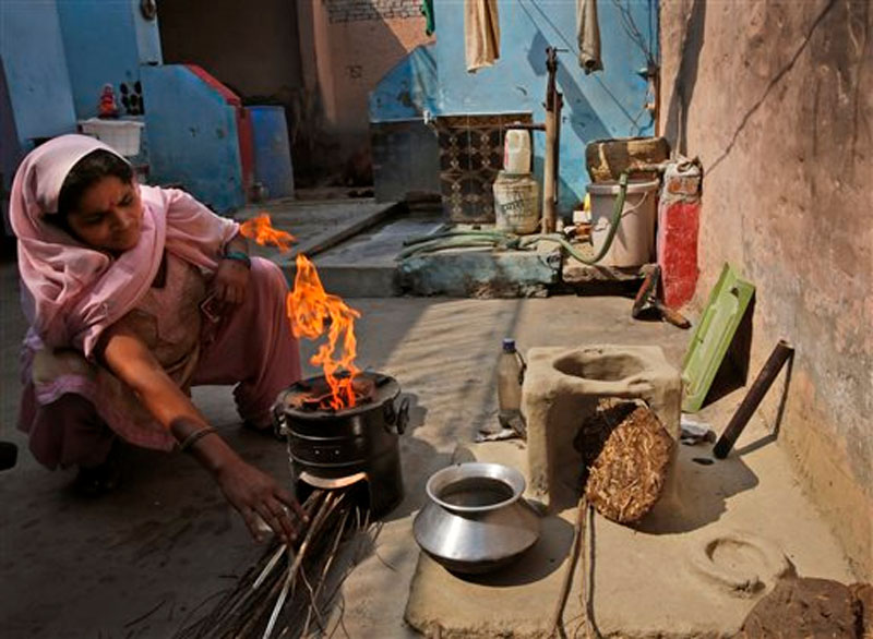 Indian woman Rekha Devi lights her new fuel-efficient cook stove next to her old clay stove in her house at a village near Bulandshahr, Uttar Pradesh, India, She now needs half the time to cook dinner as before on October 19, 2015. Photo: AP