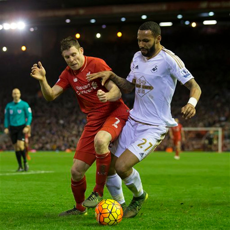 Liverpool's James Milner (left) fights for the ball against Swansea's Kyle Bartley during the English Premier League soccer match between Liverpool and Swansea at Anfield Stadium, Liverpool, England on Sunday, November 29, 2015. Photo: AP