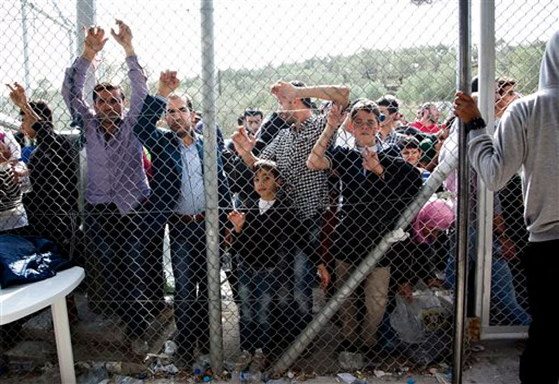 Migrants and refugees wait outside a fence of the Moria camp on the eastern Aegean island of Lesbos, Greece on October 10, 2015. Photo: AP