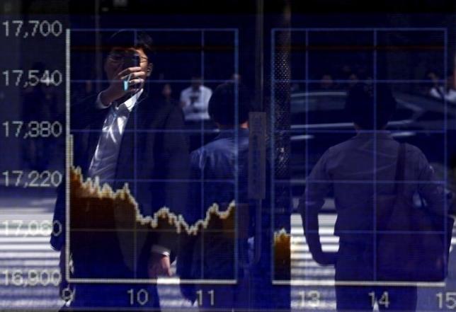 A man using a smartphone is reflected on a graph showing today's movements of Nikkei share average outside a brokerage in Tokyo, Japan, September 29, 2015. Photo: Reuters