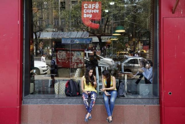 Girls sit at the window of a Cafe Coffee Day outlet in Mumbai, February 25, 2015. Photo: Reuters