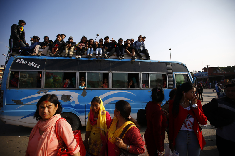 Passengers travel on the roof of a bus at Old Bus Park, Kathmandu on Saturday, November 14, 2015. As the festive season of Tihar ended, many people are returning to their homes from villages and as life is heading back to normal inside the city. Photo: Skanda Gautam