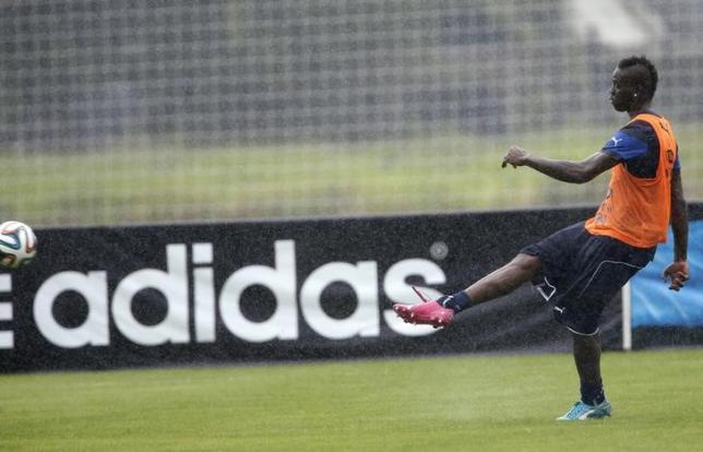 Italy's national soccer player Mario Balotelli kicks the ball as an Adidas advertising banner is seen during a training session ahead of the 2014 World Cup at the Portobello training center in Mangaratiba June 10, 2014. REUTERS/Alessandro Garofalo