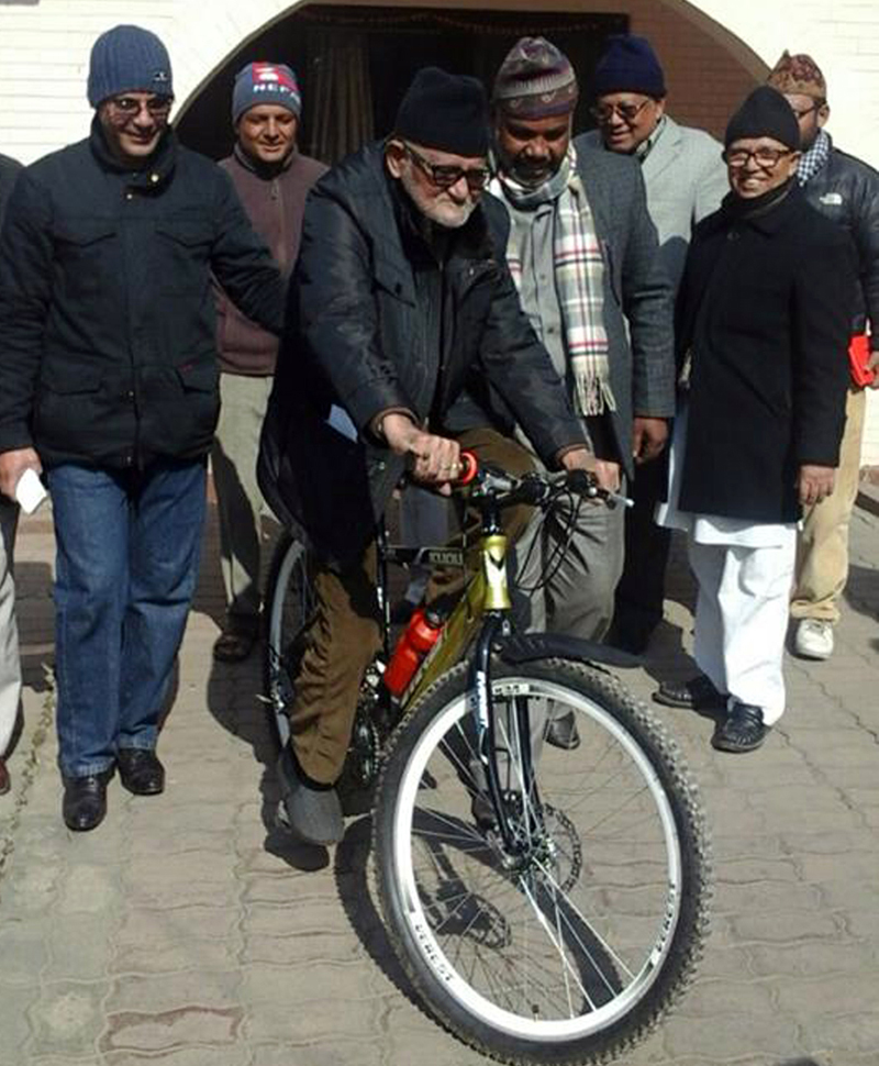 Nepali Congress President Sushil Koirala rides on a bicycle after being gifted by the Environment-friendly National Campaign, in Kathmandu, on Wednesday, December 30, 2015. Photo: RSS
