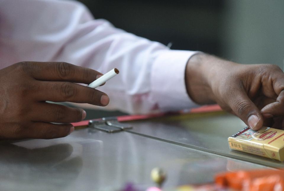 An Indian smoker purchases a single cigarette from a roadside shop in New Delhi on November 26, 2014. Photo: AFP