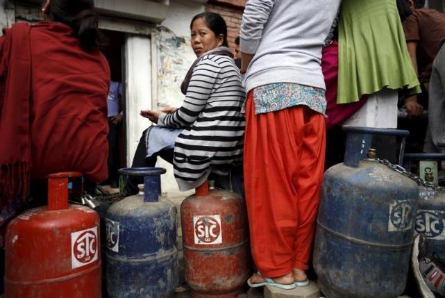 A woman sits on top of their empty cooking gas cylinders while waiting in a queue to buy cooking gas during the ongoing fuel crises that has been continuing for over a month now in Kathmandu, Nepal October 30, 2015. REUTERS/Navesh Chitrakar