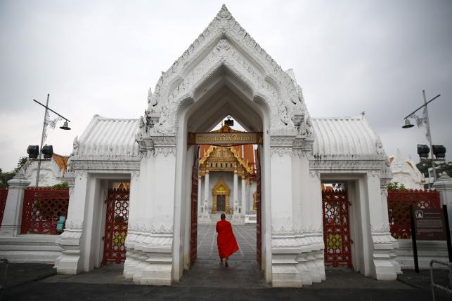 A Buddhist monk enters a temple after receiving food early morning in Bangkok, Thailand, January 14, 2016. REUTERS/Jorge Silva