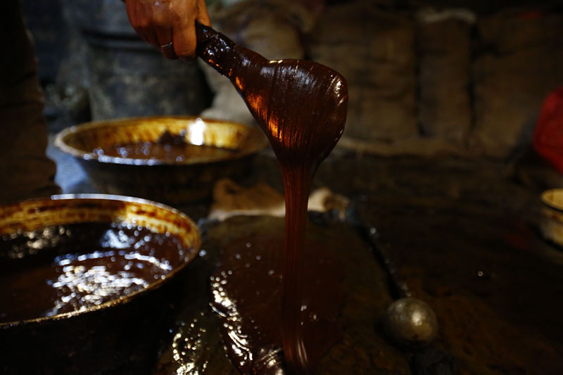 Binay Krishna Shrestha pours boiled molasses onto a stone for cooling to prepare Chaku, traditional candy, at Shakti Chaku shop in Ombahal Gache, Lalitpur on Friday, January 8, 2016. Photo: Skanda Gautam/THT