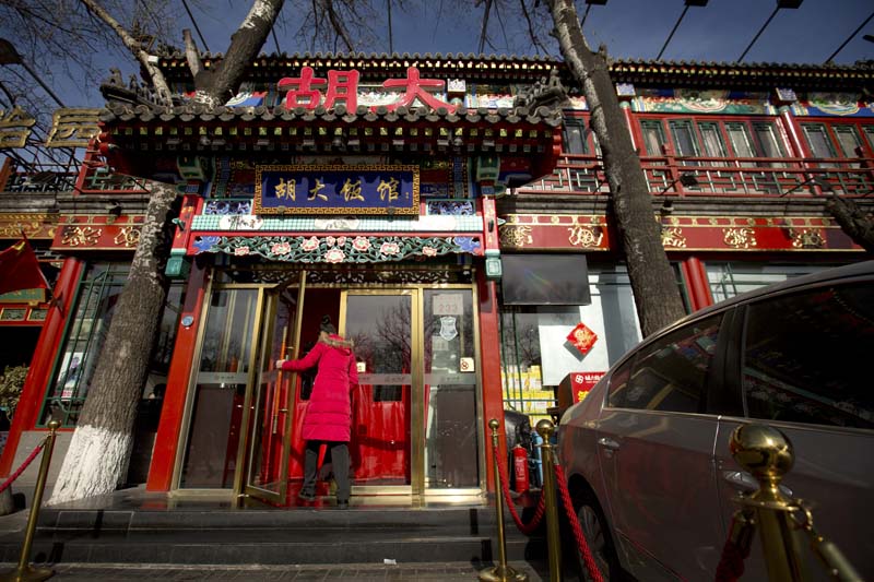 A hostess walks through the door of a branch of the Hu Da hot pot restaurant chain in Beijing, on Friday, January 22, 2016. Photo: AP