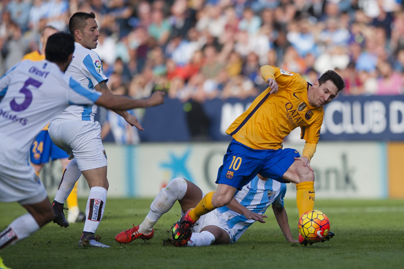 Barcelona's Lionel Messi (right) beats past Malaga players during their Spanish League match at the La Rosaleda Stadium in Malaga on Saturday. Barcelona won the match 2-1. Photo: AP