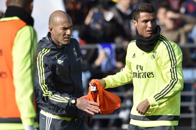 Real Madrid's Cristiano Ronaldo (right) gives a bib to club's newly-appointed coach Zinedine Zidane during his first team training session at the Alfredo di Stefano Stadium in Valdebebasm on Tuesday. Photo: AFP