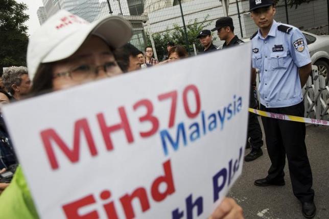 A woman whose relative was aboard Malaysia Airlines flight MH370 holds placard after police stopped protesting relatives from entering a road leading to the Malaysian embassy in Beijing August 7, 2015. Photo: Reuters