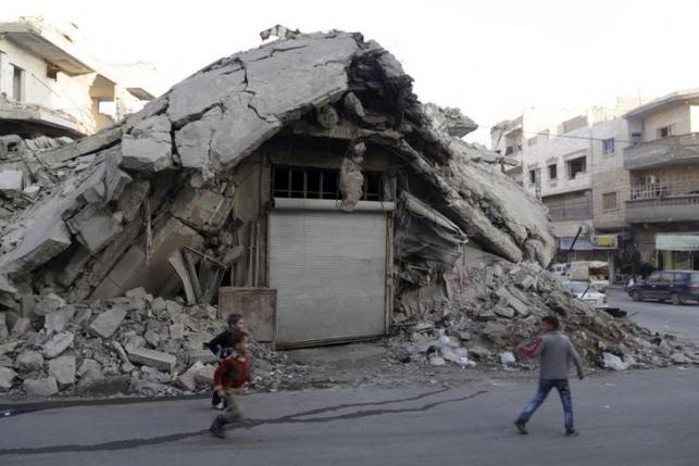 Boys run in front of a damaged building in the rebel-controlled area of Maaret al-Numan town in Idlib province, Syria, December 29, 2015.  Photo: AP