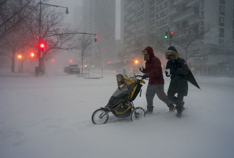 Sean Jackson and Gina Del Tatto push their child, Hayes Jackson, in a stroller as heavy snow falls in New York's Upper West Side, on Saturday, January 23, 2016, as a large winter storm rolls up the East Coast. Photo: AP