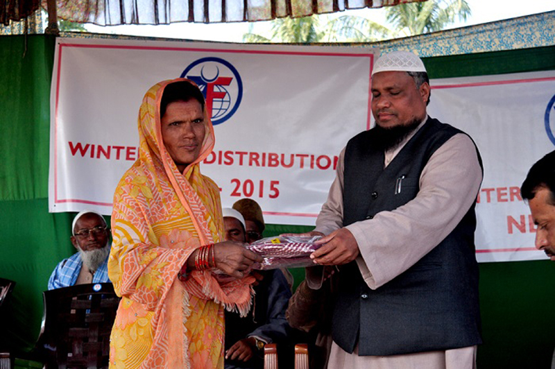 Representative of Millat Education and Welfare Society (right) distributes warm clothes to a woman in Narsing-1 of Sunsari district, on Saturday, January 2, 2016. Photo: Niroj Koirala