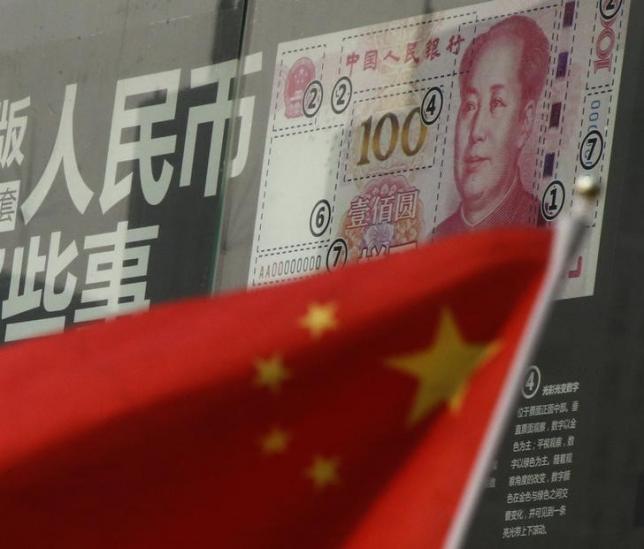 China's national flag is seen in front of a poster explaining the design of new 100 yuan banknote at a branch of a commercial bank at a business district in Beijing, China, January 21, 2016. REUTERS/Kim Kyung-Hoon