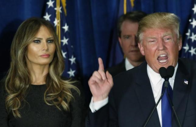 Republican U.S. presidential candidate Donald Trump gestures during his victory speech as his wife Melania, looks on at his 2016 New Hampshire presidential primary night rally in Manchester, New Hampshire February 9, 2016.  REUTERS/Jim Bourg