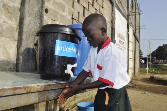 A boy washes his hands as part of Ebola prevention methods, before school starts in Paynesville, Liberia, November 24, 2015.  REUTERS/James Giahyue/Files