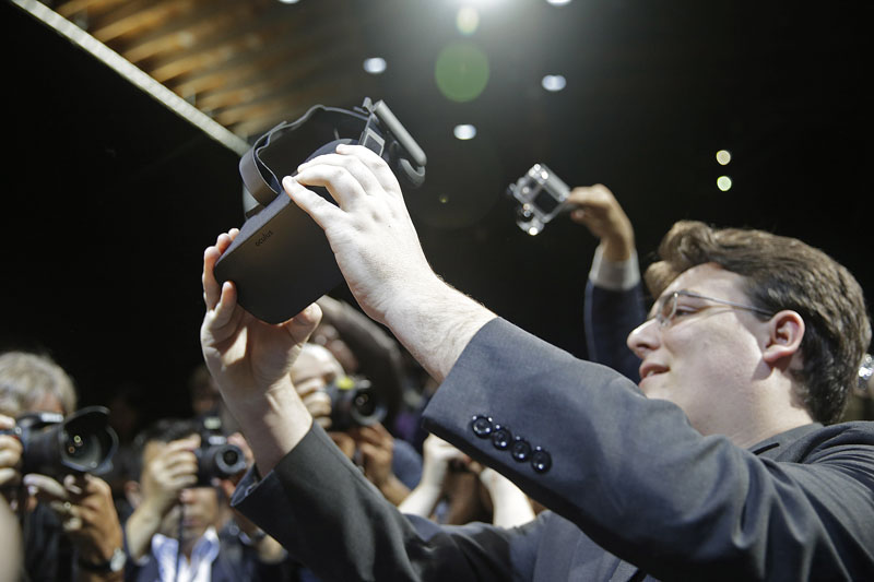 Oculus founder Palmer Luckey holds up the new Oculus Rift virtual reality headset for photographers following a news conference, in San Francisco, on June 11, 2015. Photo: AP/ File