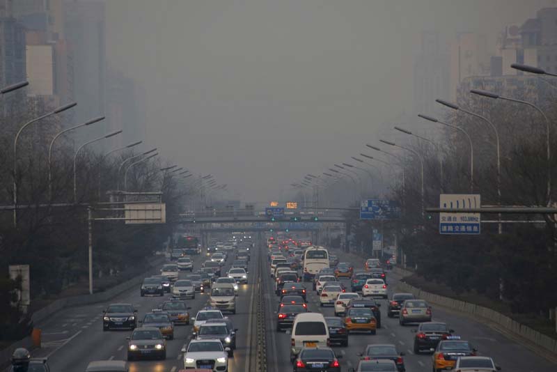 Cars are seen with headlights switched on for better vision during daytime in smog, in Beijing, China, on December 19, 2015. Photo: Reuters/ File