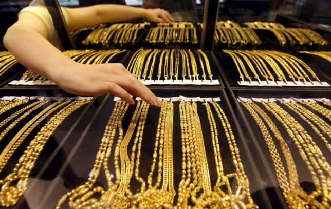 An employee arranges gold jewellery in the counter as her arm is reflected in the mirror at a gold shop in Wuhan, Hubei province, in August 25, 2011 file photo. REUTERS/Stringer/Files